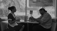 a man and woman sitting at a table in a diner