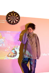 a girl standing in front of a screen with a dart board