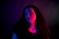 a woman with long curly hair standing in front of a colorful background