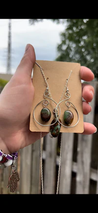 a person holding up a necklace and earrings