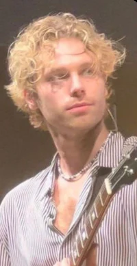 a man with curly hair holding a guitar