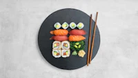 japanese sushi on a black plate with chopsticks