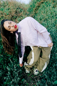 a woman in a pink shirt leaning over a bush