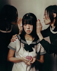 three girls in school uniforms holding a heart