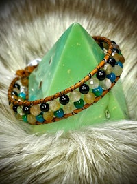 a bracelet with multi colored stones on top of a furry blanket