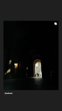 a black and white image of people walking through a dark hallway