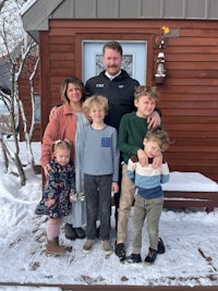 a family posing in front of a house in the snow