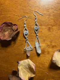 a pair of earrings with crystals and roses on a wooden table