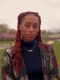 a black woman with dreadlocks standing in a park