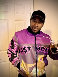 a man wearing a purple jacket holding a drink