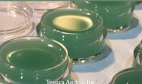 a jar of green lip balm on a table