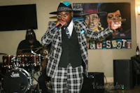 a man in a plaid suit singing into a microphone