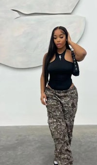 a woman in a camouflage outfit standing in front of a painting