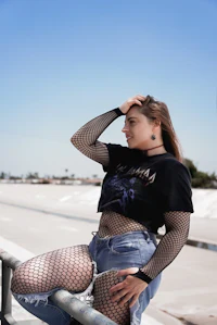 a woman in fishnets posing on a railing