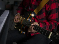 a person playing an electric guitar in front of a keyboard