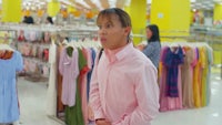 a woman in a pink shirt is standing in a clothing store