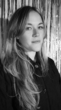 a black and white photo of a woman in front of a curtain