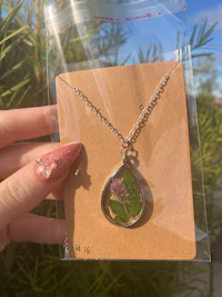 a person holding a necklace with a flower in it
