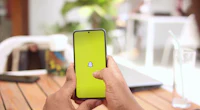 a person holding a phone with a yellow button on it