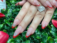 a woman's hand with red and white nails and a ring