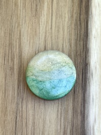 a green and white stone on top of a wooden table