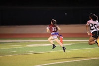 two girls running on a football field at night