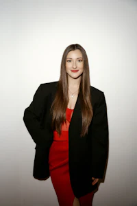 a woman in a black blazer and red dress posing for a photo