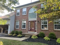 a brick home with a front door and landscaping