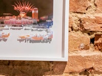 a framed photograph of a fireworks display on a brick wall