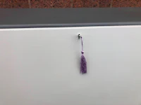 a purple tassel hanging from a white cabinet