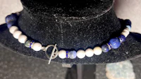 a necklace with blue and white beads on a mannequin