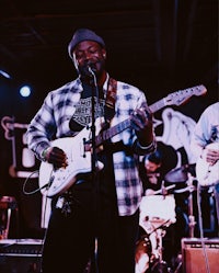 a group of men playing guitars in front of a microphone