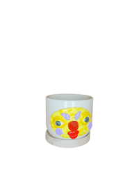 a white cup with a yellow face on it