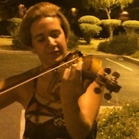 a woman playing a violin in a parking lot at night