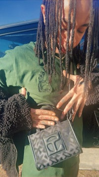 a man with dreadlocks holding a purse