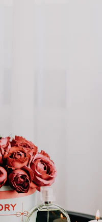 a vase of roses on a table next to a candle