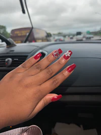a woman's hand with red nails and a car in the background