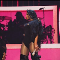 a woman in a black outfit is performing on stage