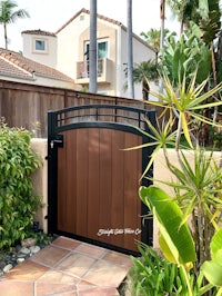 a wooden gate in a backyard with plants and trees