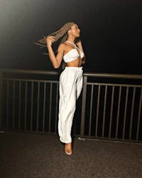 a woman in white pants standing on a railing at night