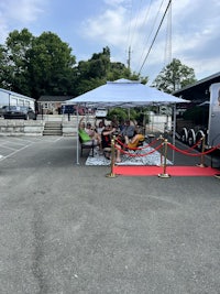 a group of people are sitting on a bench in front of a tent
