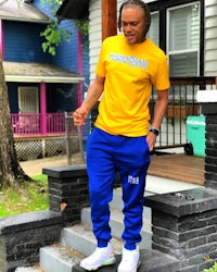 a man wearing a yellow t - shirt and blue joggers