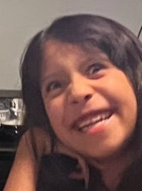 a young girl is smiling while sitting in a chair