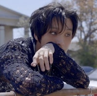 a young man leaning against a fence