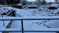 a sidewalk covered in snow with a railing