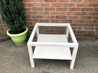 a white side table with a potted plant next to it