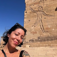 a woman with tattoos taking a selfie in front of a building