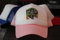 a white, pink and blue hat with an elephant on it