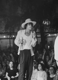 a man in a hat singing on stage in front of a crowd