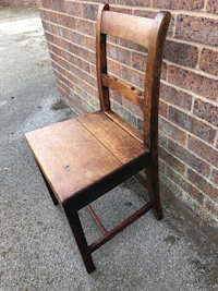 a wooden chair against a brick wall